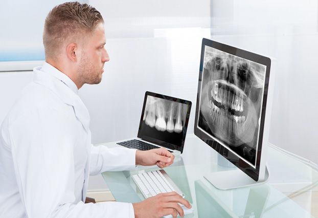 Man looking at dental x-rays on monitor